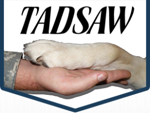 TAD SAW logo with a Soldier's hand held out with a dog's paw on top.